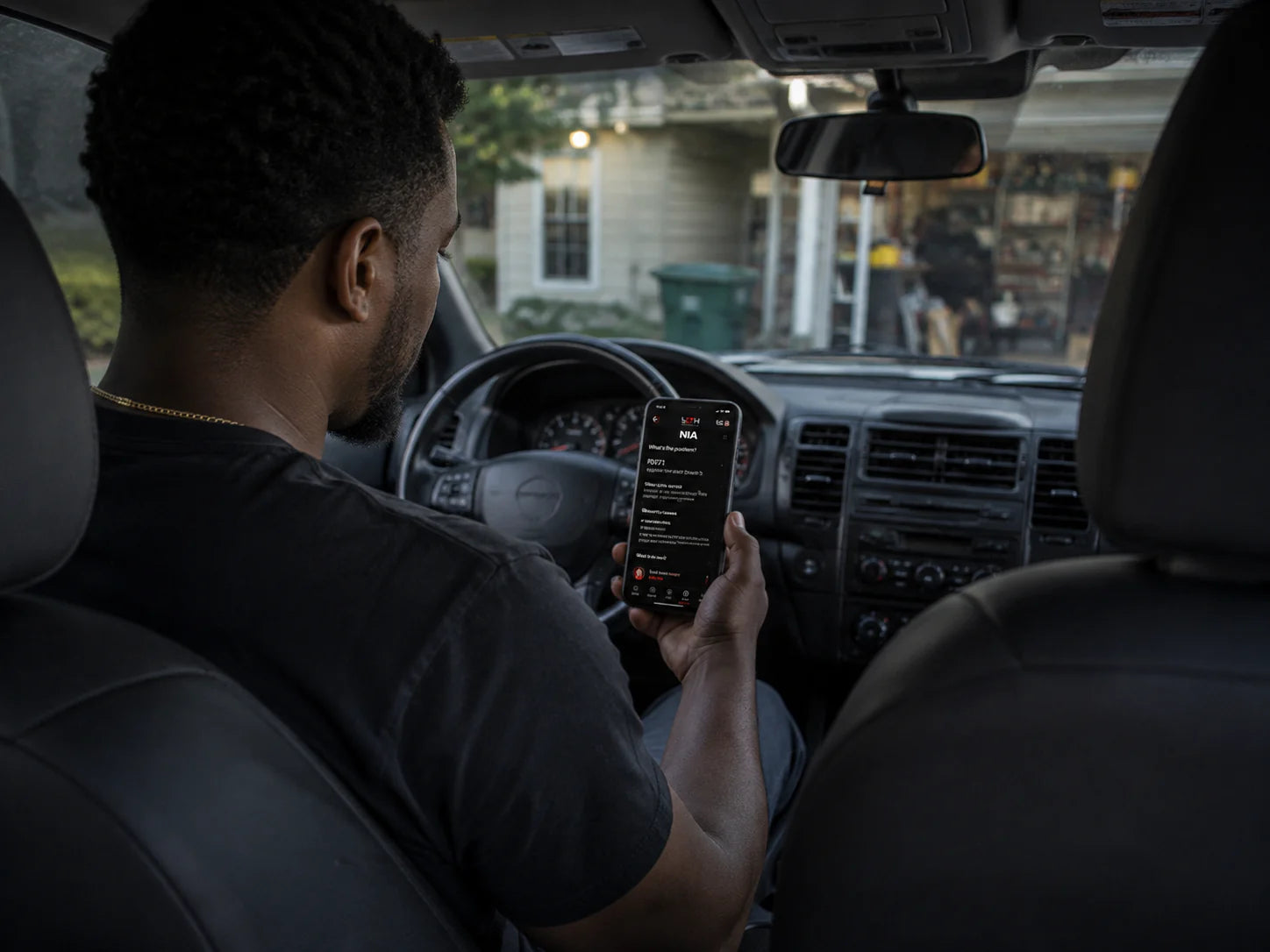 Person reviewing diagnostic answers from Nia on a phone while seated in a parked vehicle